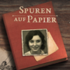 Screenshot aus dem Spiel "Spuren auf Papier", einem Spiel über die Krankenmorde während der NS Zeit. Tisch mit Tagebuch, darauf Photo eines jungen Mädchens. Auf dem Tisch liegen Photos und Zeichnungen.