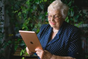 Alte Frau mit Apple Tablet in der Hand.