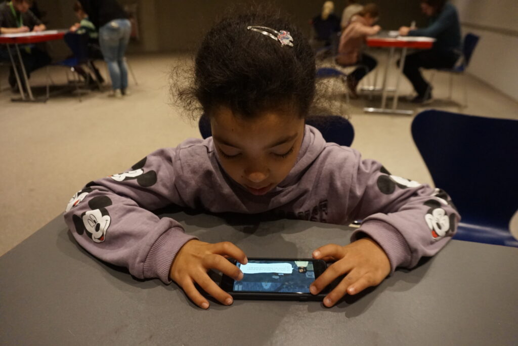 Photo vom Testing des Mobile Games "Eiszeitwelten". Das Spiel ermöglicht eine digitale Entdeckungsreise in die Eiszeit! Mädchen spielt das Spiel und schaut dabei gebannt aufs Smartphone
